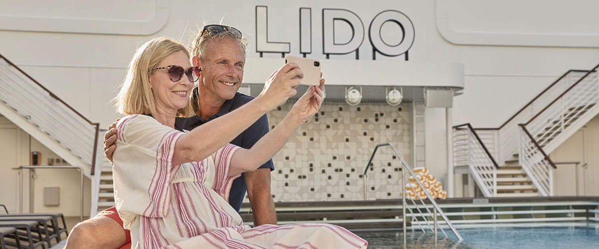 A couple taking pictures together by the Lido on Spirit of Adventure